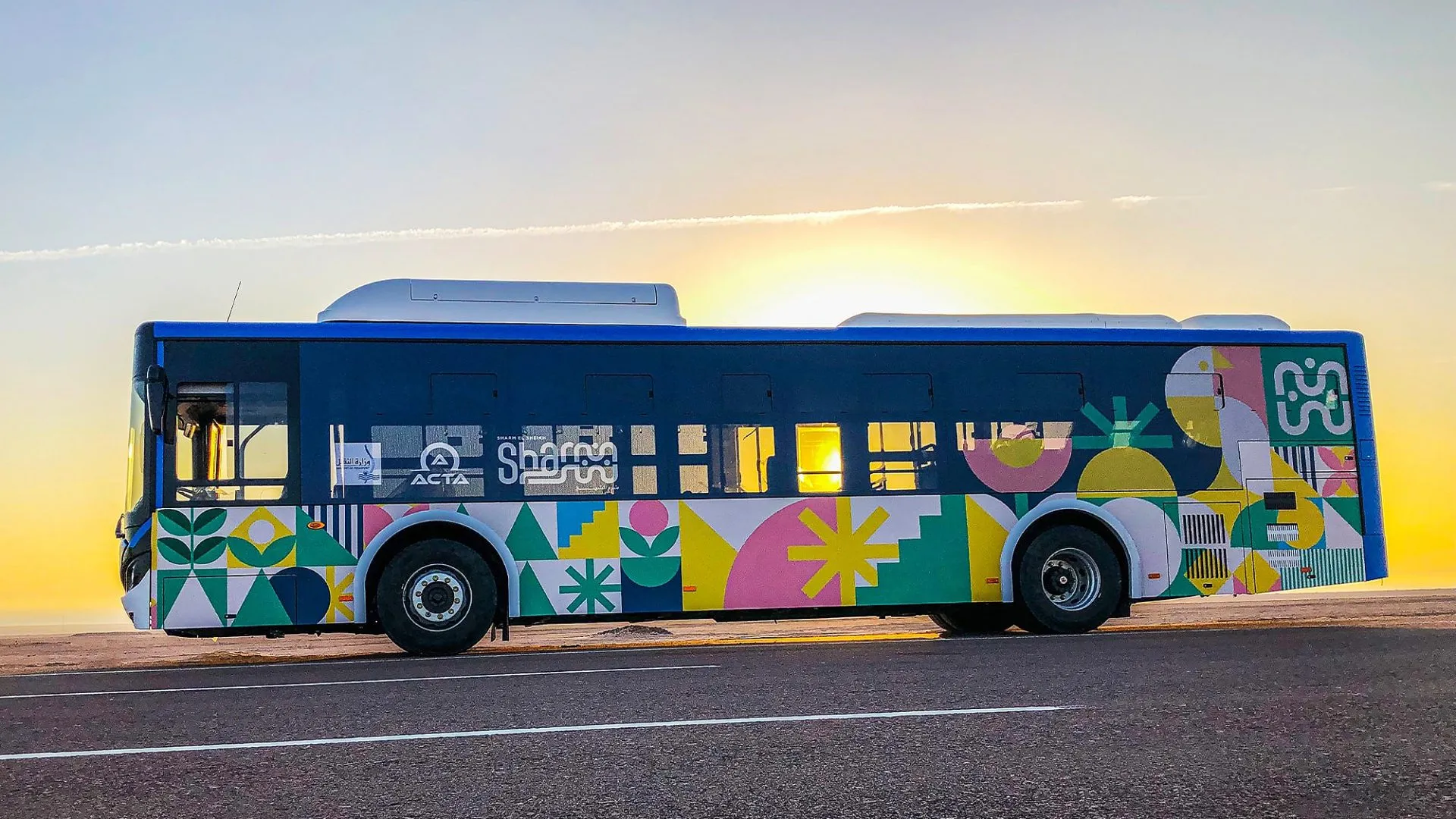 Modern Sharm El-Sheikh city bus with colorful livery at sunset.