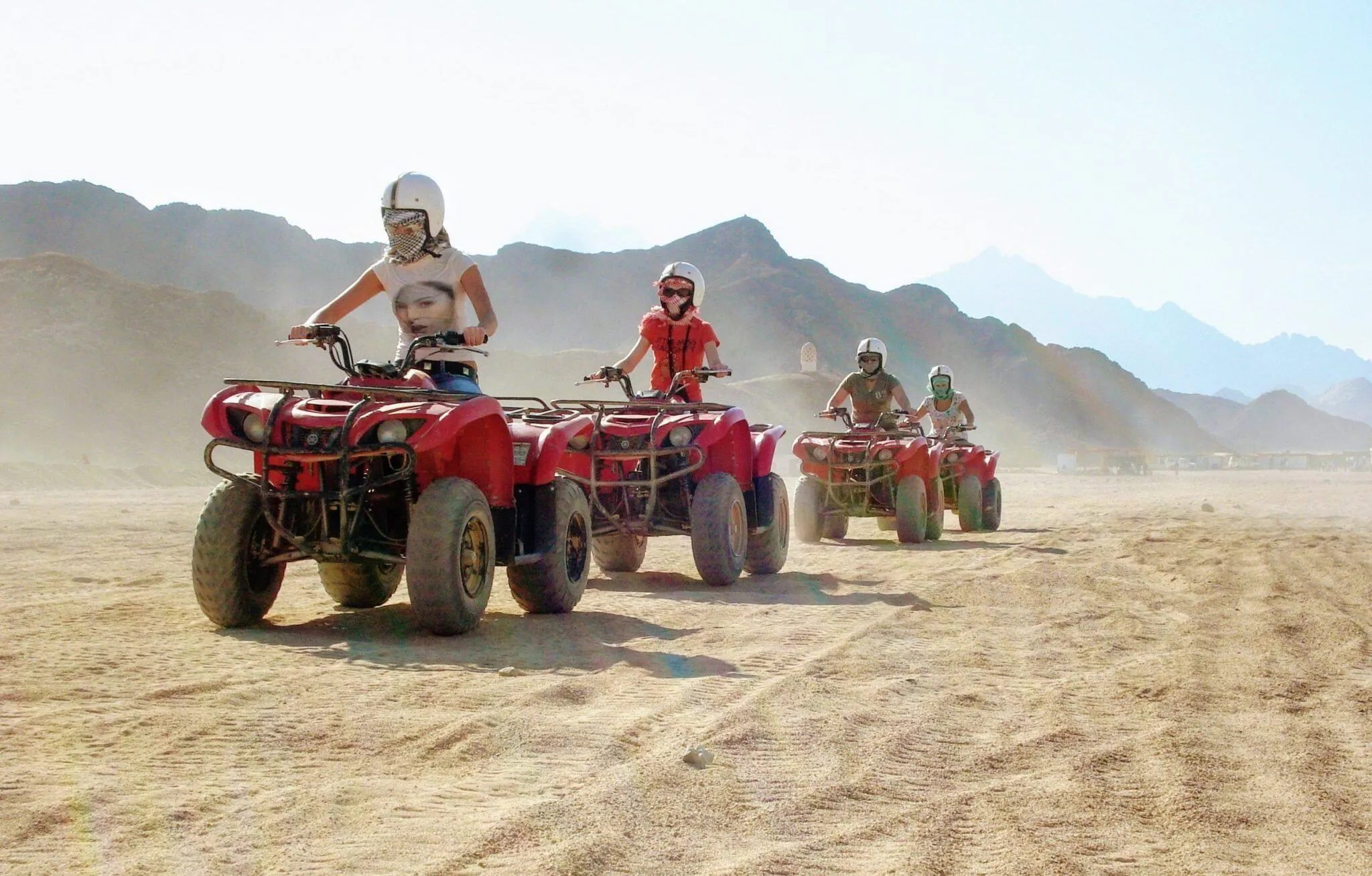 Adventurous quad bike safari riders in dusty Sinai desert near Sharm El-Sheikh.