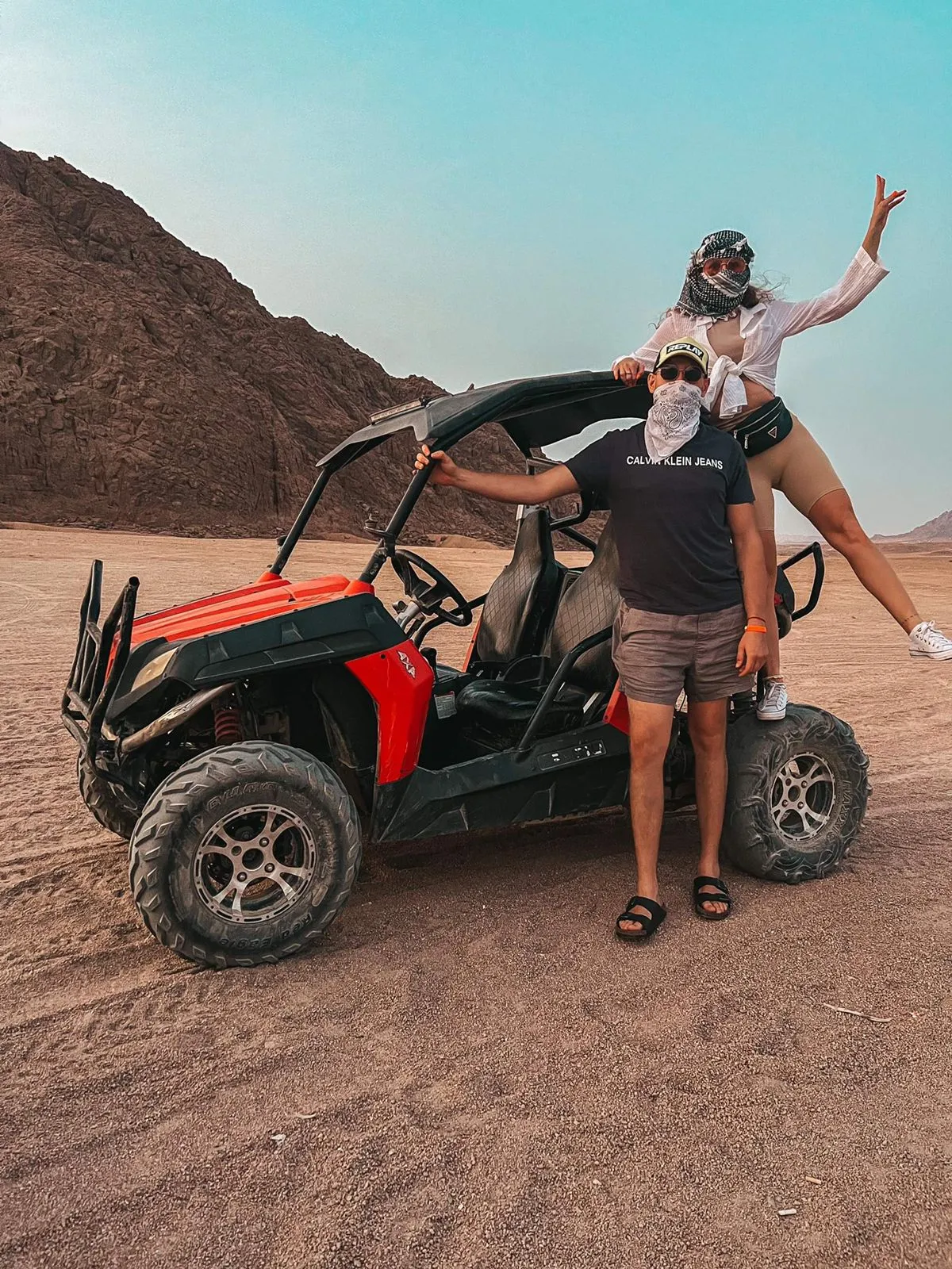 Adventurous couple with red and black dune buggy in the Sinai desert.